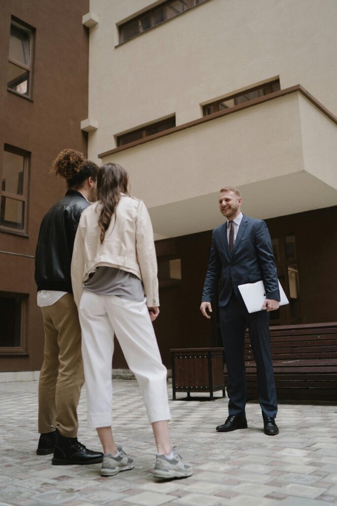 A loan agent talking with two applicants who are standing and chatting.