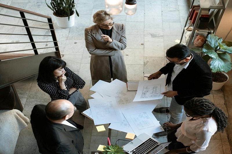 A diverse group of business professionals gathered around a conference table, engaging in a discussion about project financing