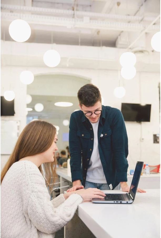 Two entrepreneurs discussing their startup business plan with notes and a laptop, considering options for startup loans.