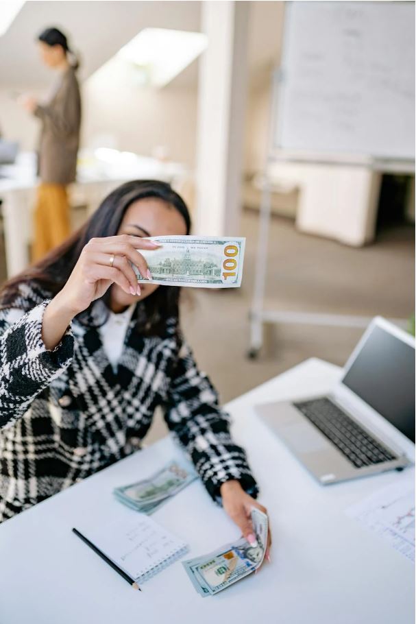 Woman holding a 100 dollar bill, symbolizing financial support for working capital loans.